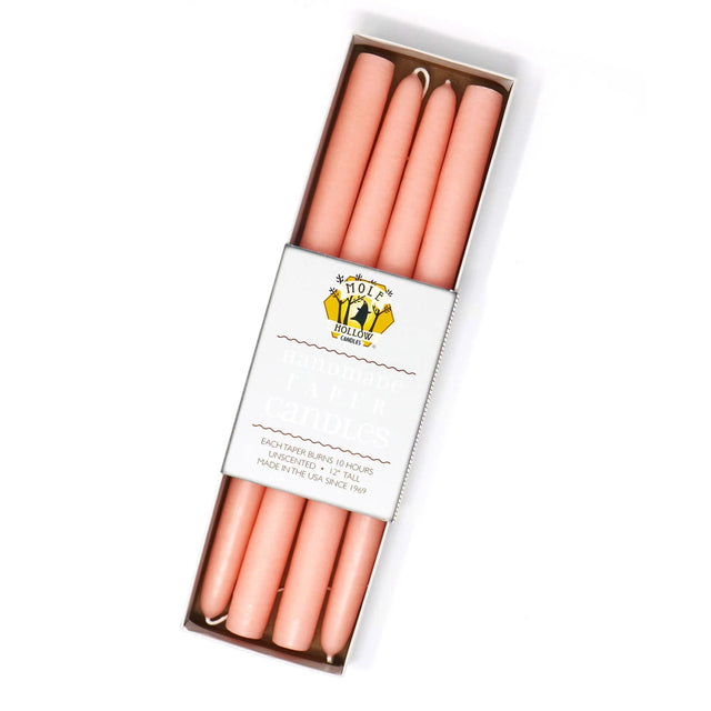 four peach colored taper candles in a rectangular box with a white label