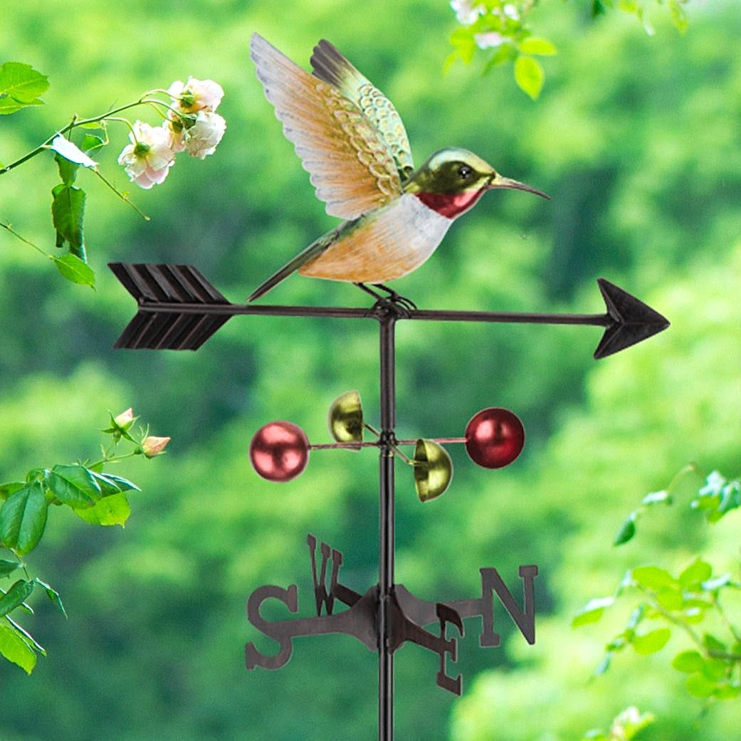 the hummingbird weathervane stake in a lush green garden