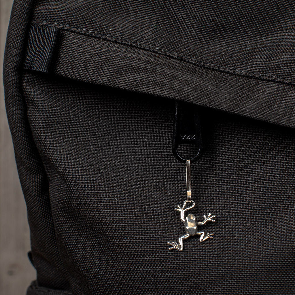 the tree frog zipper pull attached to the zipper of a black backpack