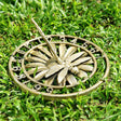 On a lawn sits a sundial of a dragonfly resting on a flower