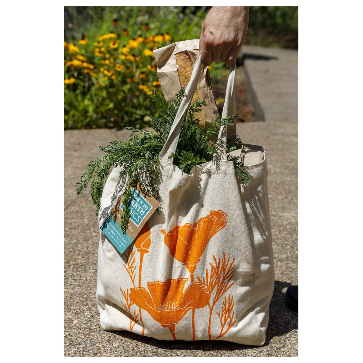 the farmer's market tote outdoors filled with overflowing grocery items with the orange poppy side showing