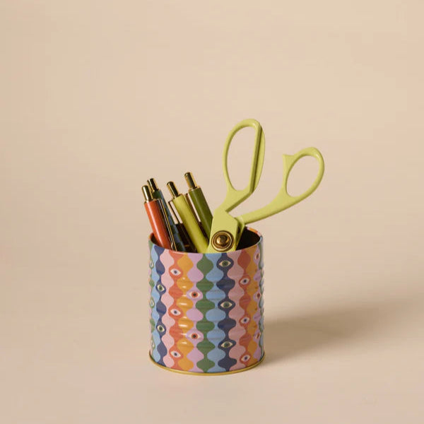 Colorful geometric-patterned canister with pens and scissors on a beige background