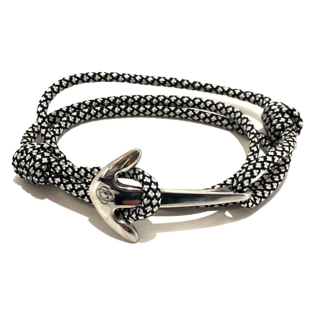 a black with white diamond pattern cord wrap bracelet that is held in place with a silver anchor charm
