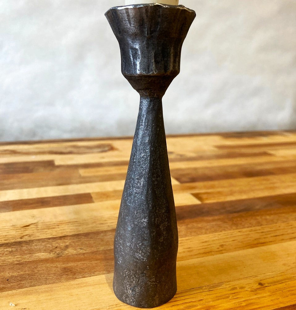 a closeup of the detail of a forged metal candlestick showing the subtle detail in the metalwork