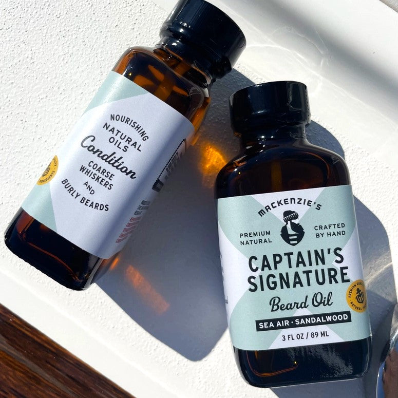 a close up of two bottles of the Captain's Signature Beard oil on the deck of a boat