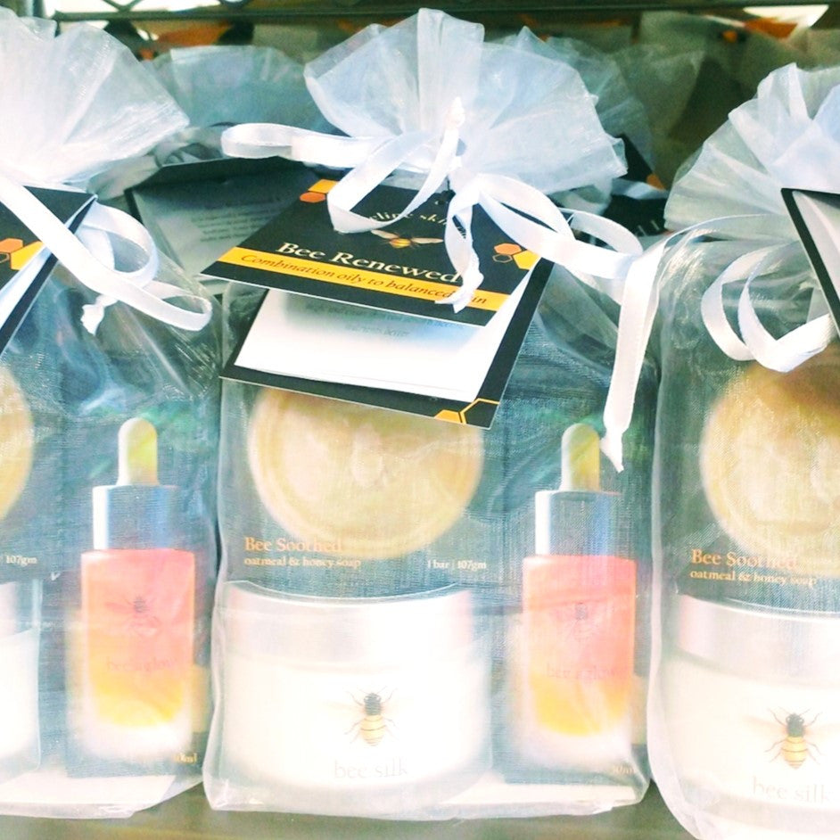 a tight grouping of the Bee Renewed I kits packaged in their white organza bags with white ribbon and attached card with product info and uses