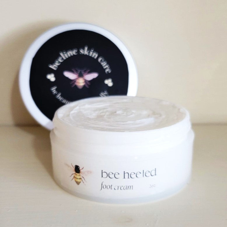 a close up of the bee heeled foot cream, the lid of the jar is off to show the rich, creamy texture of the white foot cream
