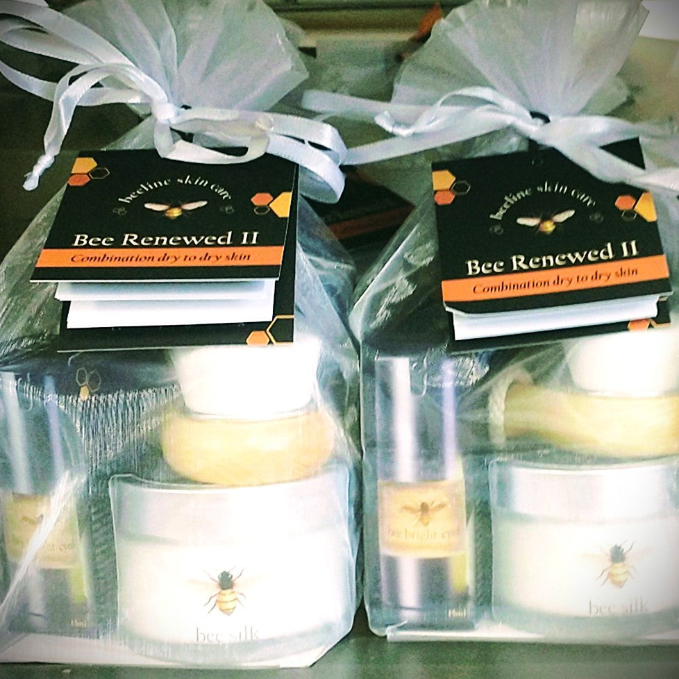 a tight grouping of the Bee Renewed II kits packaged in their white organza bags with white ribbon and attached card with product info and uses
