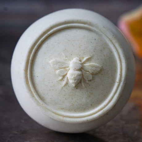 a close up of the Bee Soothed soap bar showing the circular bar of soap with the detailed anatomical honey bee imprint in the center of the bar