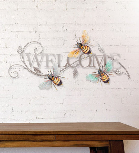 a silver welcome sign in silver metal surrounded by 3 realistically sculpted and painted bees mounted on a white brick wall
