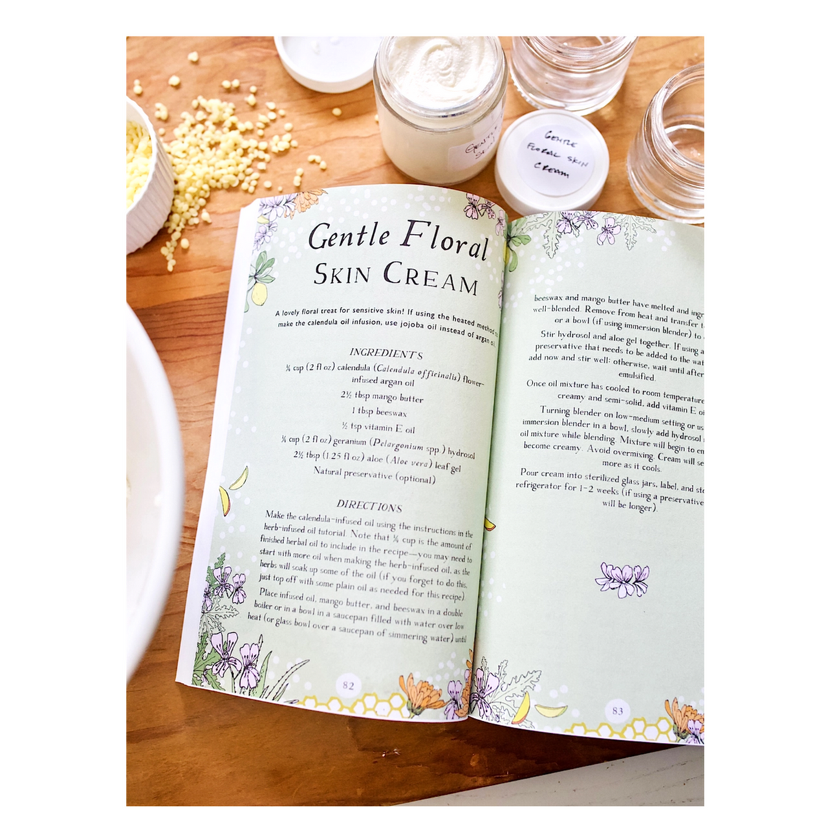 the Botanical Skin Care Recipe book on a table surrounded by jars and ingredients and open to a page with a recipe for Gentle Floral Skin Cream