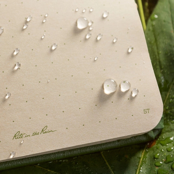 a close up of the open notebook with water beading on the surface showing the waterproof nature of the paper