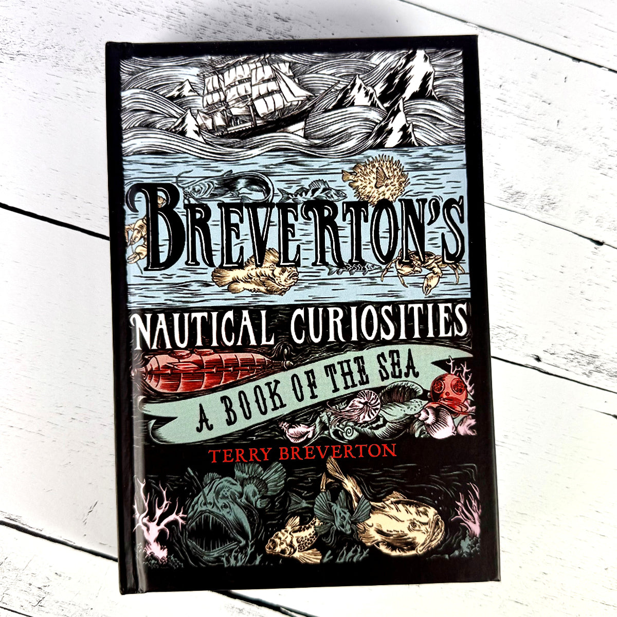 a book lying on a white wood background titled "Breverton's Nautical Curiosities: A Book of the Sea"