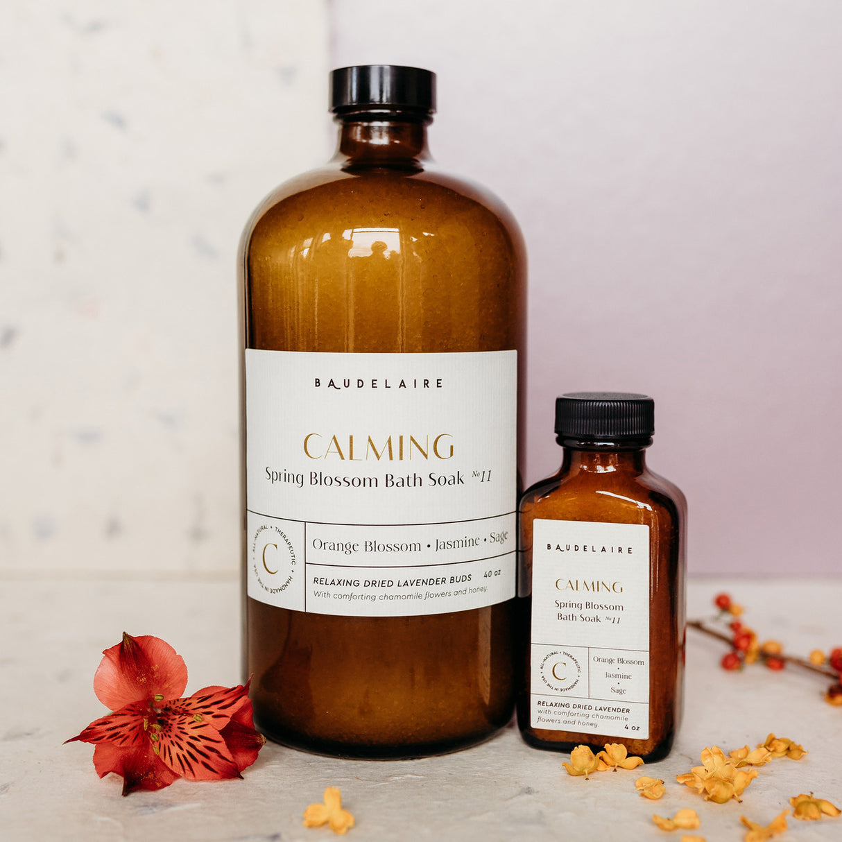 a large 40 ounce bottle of the Spring blossom soak alongside a small 4 ounce bottle of the spring blossom soak on a table surrounded by flower petals