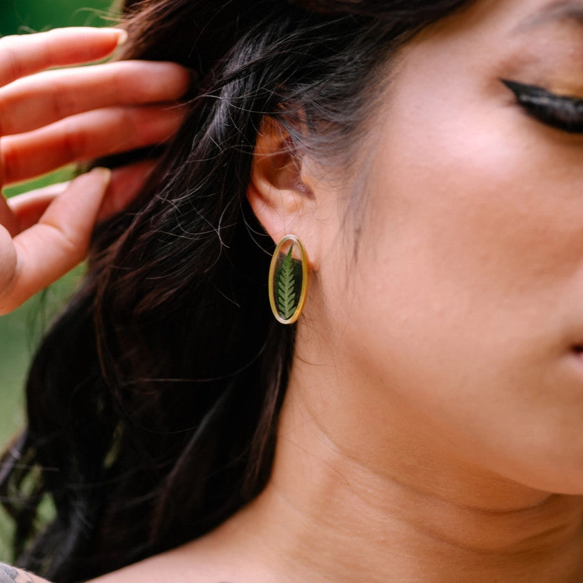 the Oval Floating Pressed Fern Post earrings on a model with dark hair