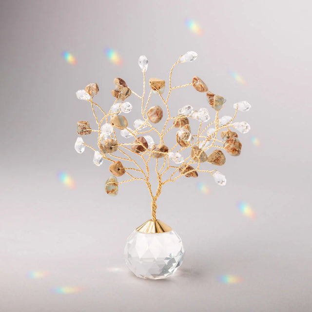 Decorative tree with gold branches and crystal base adorned with aqua terra stones and clear crystals casting tiny rainbows against the light gray background