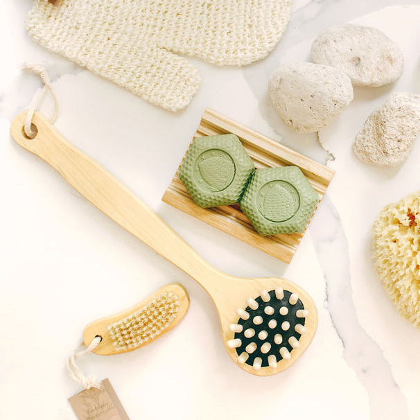 Set of natural bath tools including a brush, scrubber, and soap on a light background
