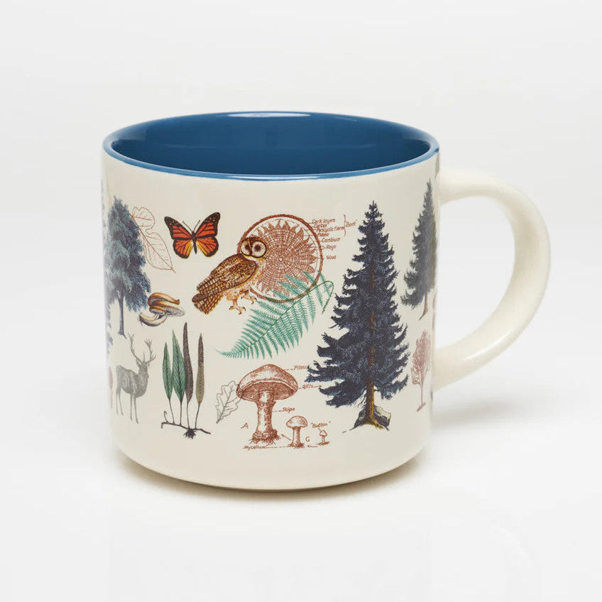 the other side of a white coffee mug with more vintage illustrations of woodland flora and fauna wrapping around it, and a solid deep blue print on the inside of the mug