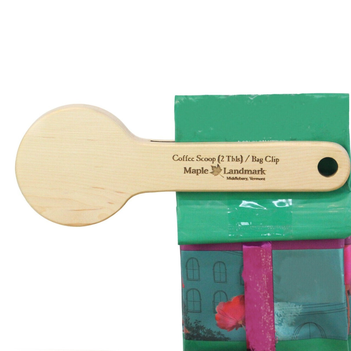 the clip end of the coffee scoop on the top of a bag of coffee holding it closed