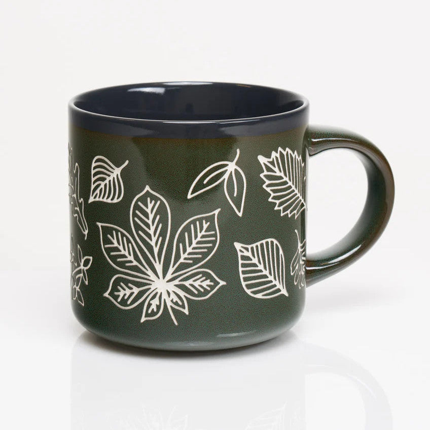 the other side of a forest green coffee mug with various leaf prints in white showing the outlines and details of various leaves in white with a vintage feel