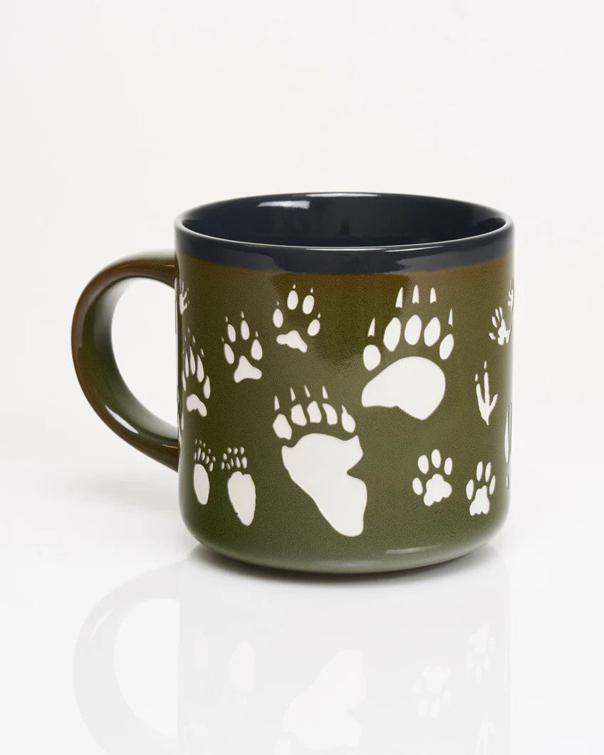 a deep green coffee mug with various animal tracks in white including paw prints, hoof prints, birds, and more