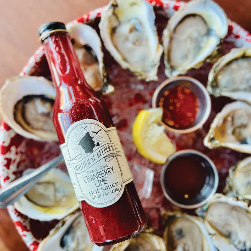 cranberry lime hot sauce bottle hovering above a platter of fresh oysters