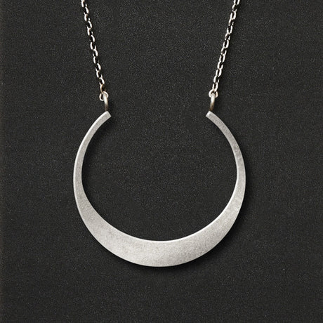 A silver necklace with a crescent moon pendant