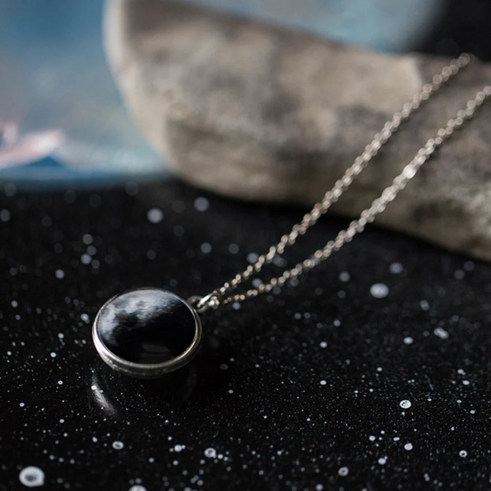 Necklace with a moon pendant on a dark surface