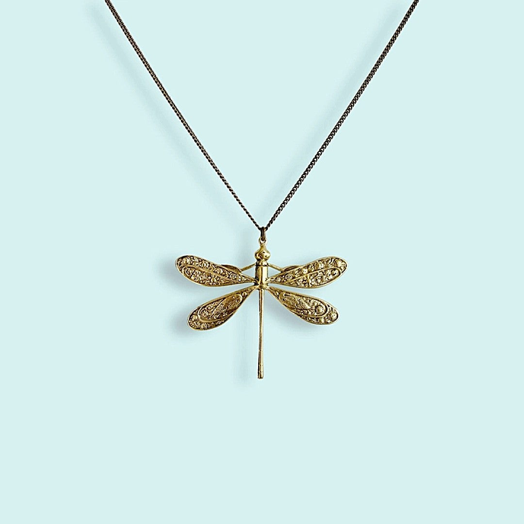 Gold dragonfly pendant necklace on a light blue background