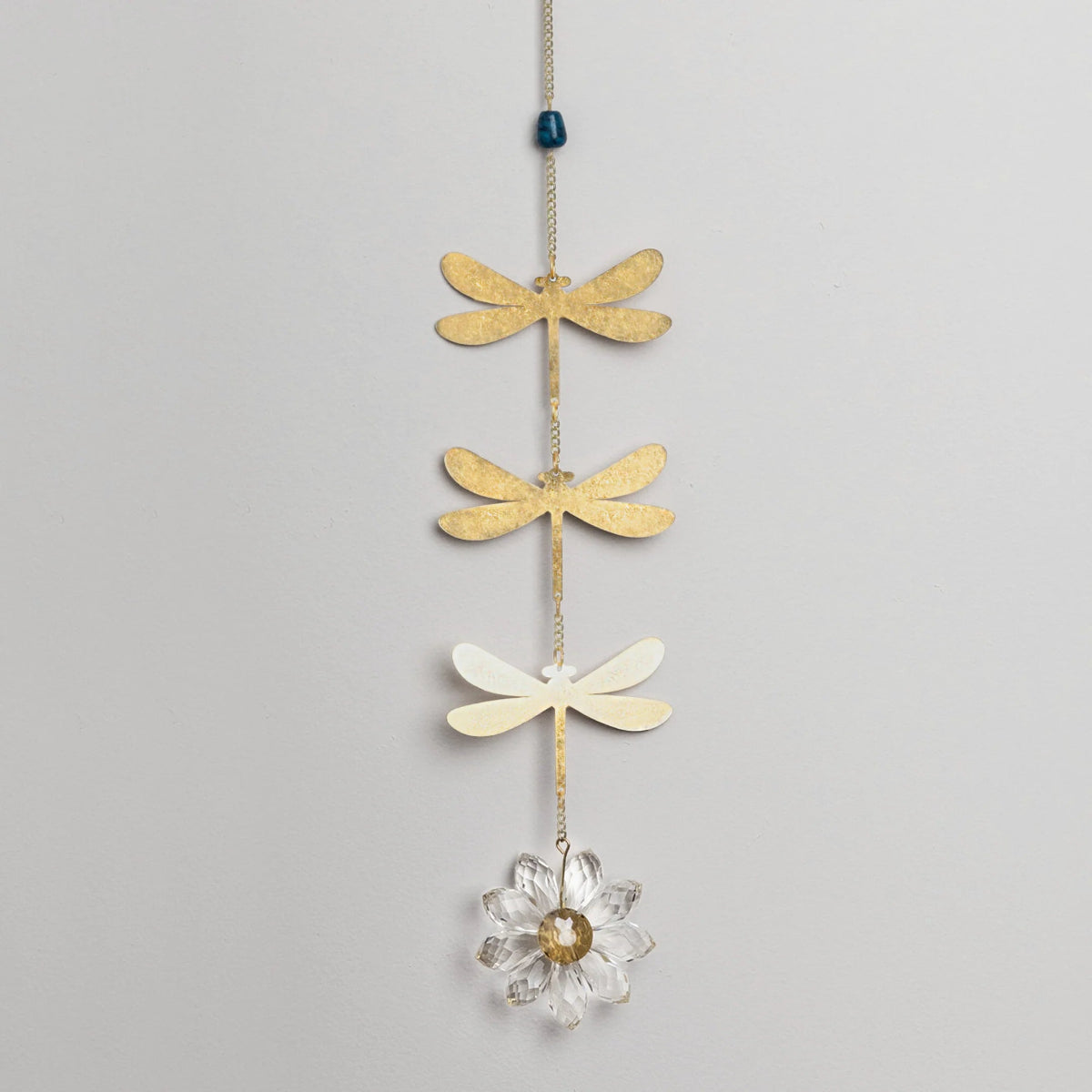 Decorative hanging chain with 3 brass dragonfly cutouts with a blue apatite stone above them and a crystal daisy hanging below