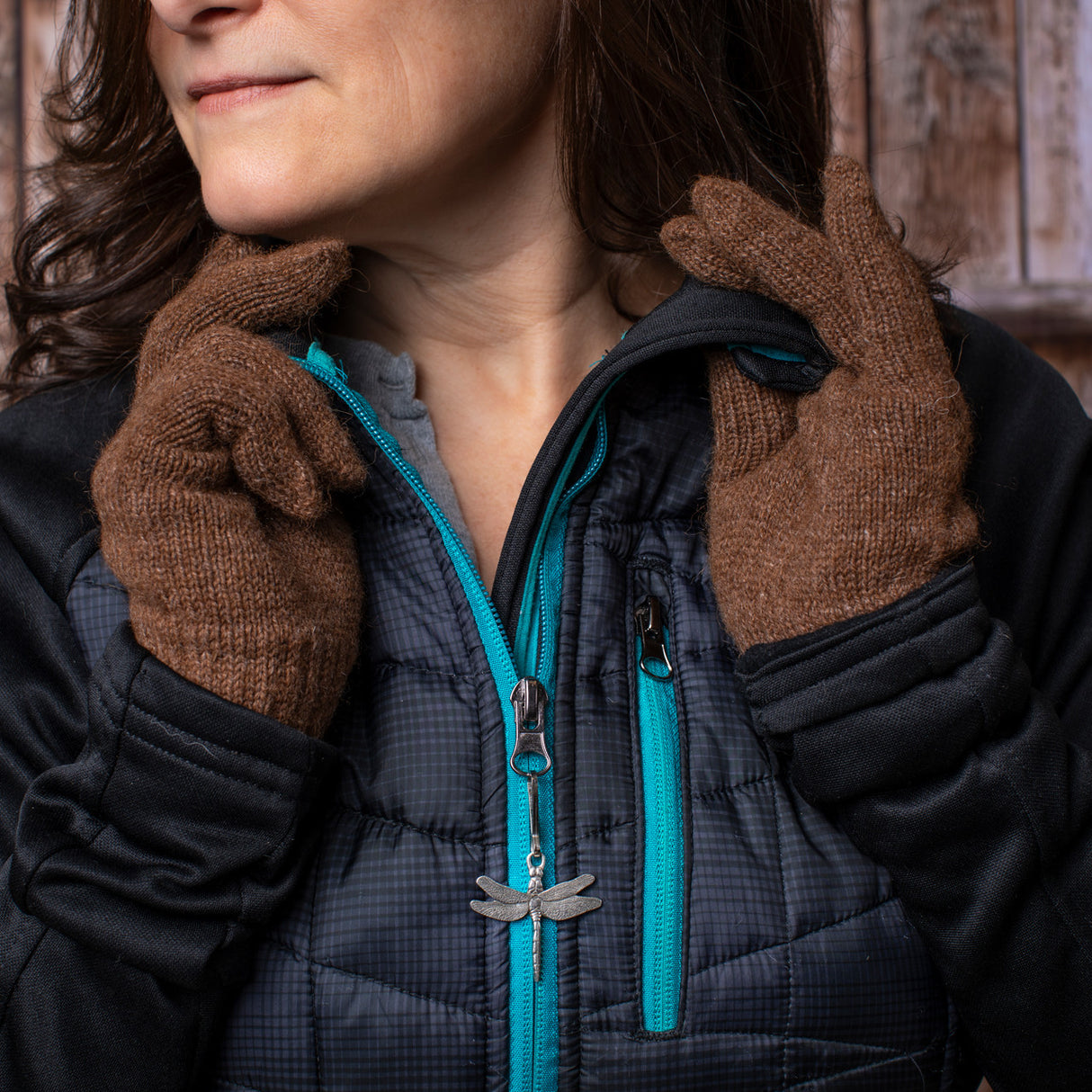 a model adjusting the collar on her black coat with the dragonfly zipper pull on her coat zipper