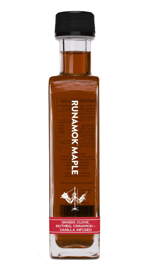 A side view of a bottle of festivus infused maple syrup against a white background