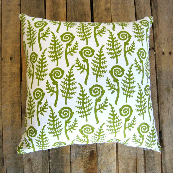 Decorative pillow with green fern pattern on a wooden background