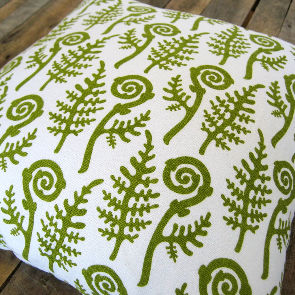 Green leaf pattern on a white pillow on a wooden surface