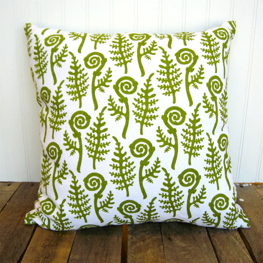 Decorative pillow with green fern pattern on a wooden surface