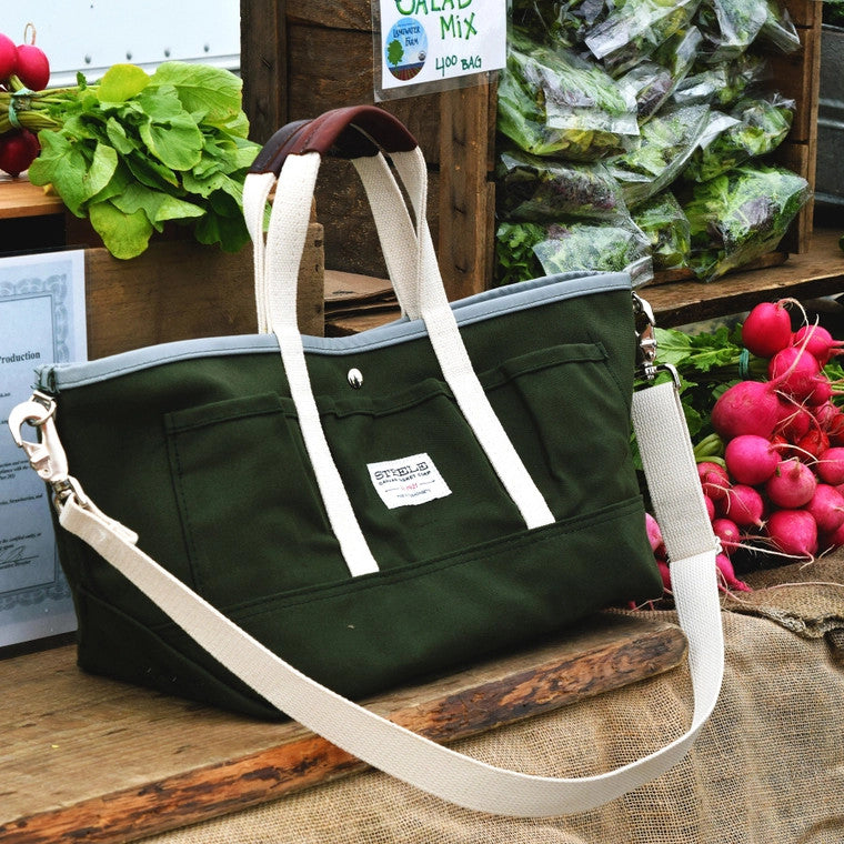 the garden tote resting on a farmer's market table alongside fresh radishes and bagged greens
