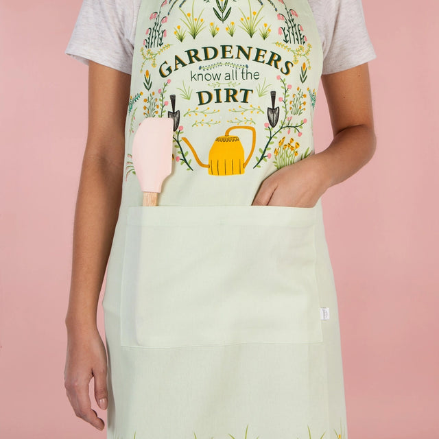 Person wearing a gardening-themed apron with a pink spatula on a pink background