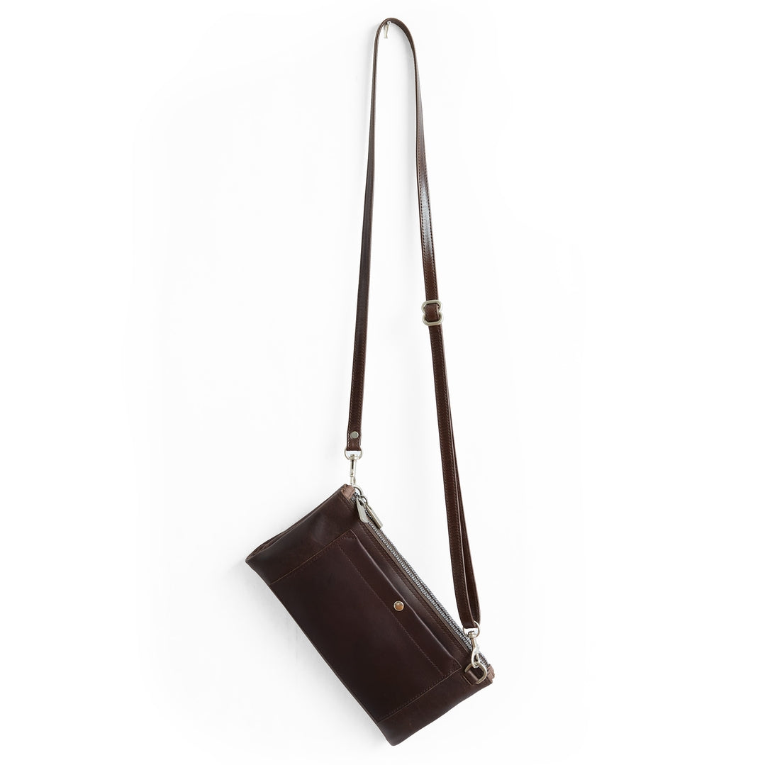 A dark brown leather crossbody bag with a long adjustable shoulder strap and silver-tone hardware, shown against a plain white background.