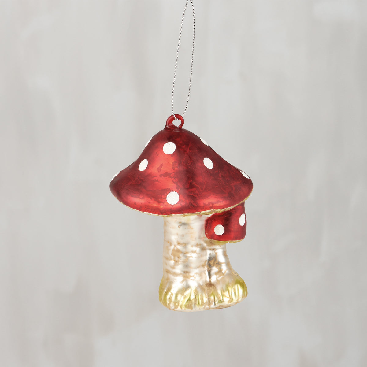 Decorative mushroom ornament with red cap and white spots on a plain background