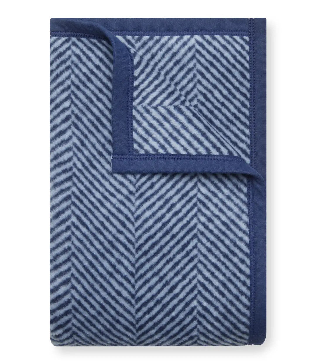 The folded Harborview Herringbone Navy Blanket with the top right corner folded over to show the reverse of the design