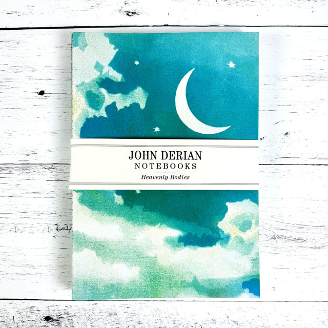 John Derian notebooks with celestial design on a wooden surface