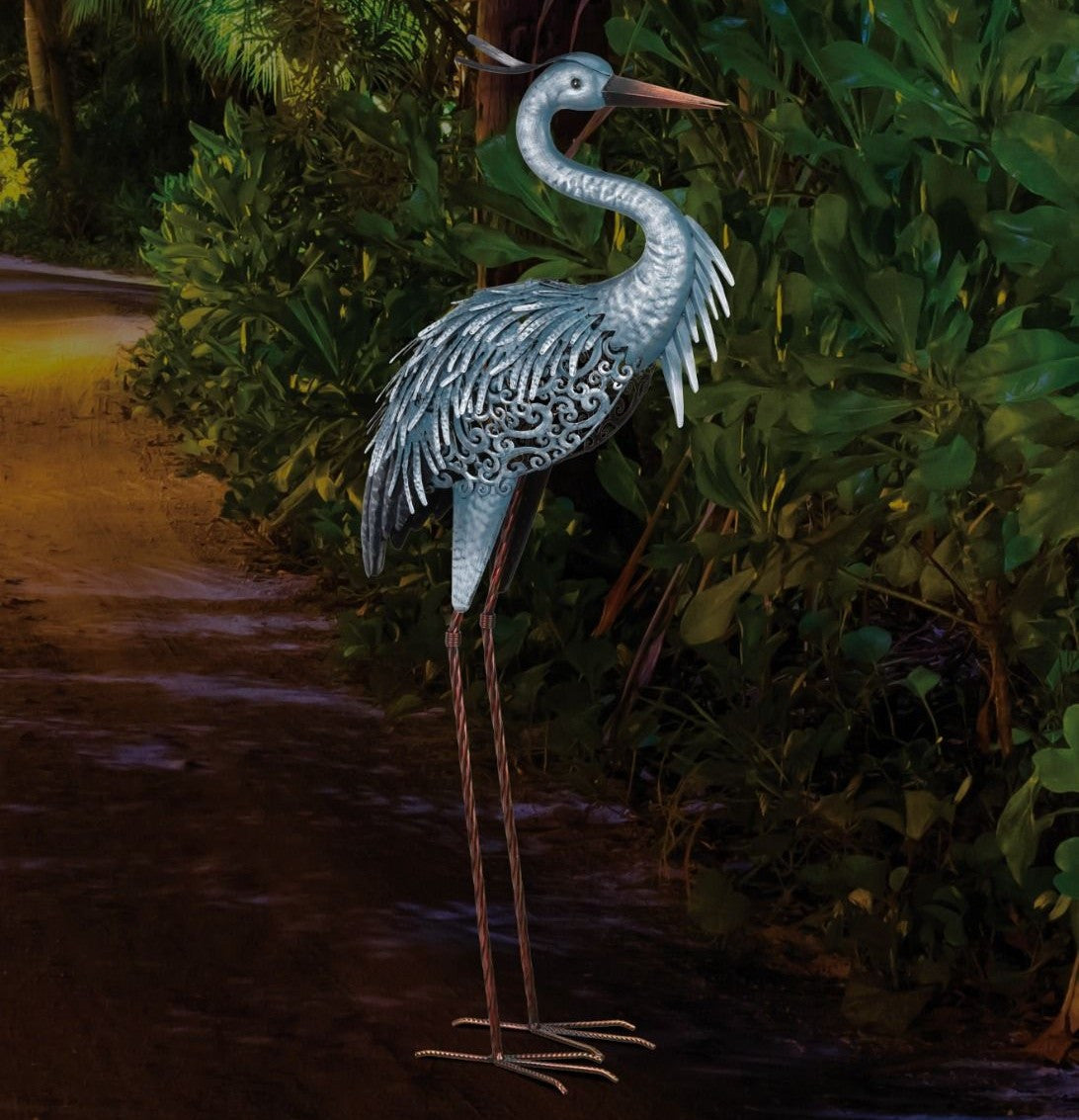 the "down" heron sculpture illuminated at night on a garden path