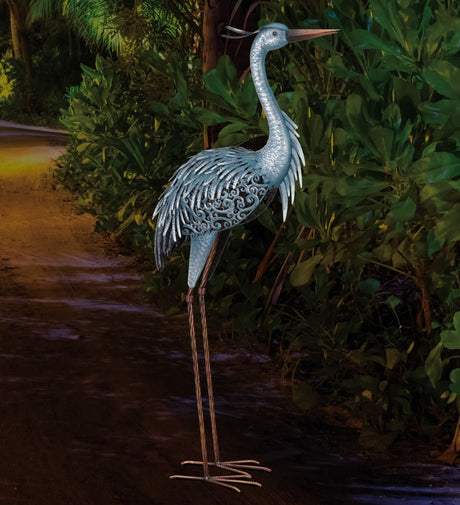 the "Up" heron sculpture shown illuminated at night on a garden path