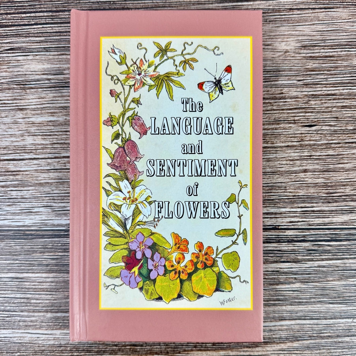 Book titled 'The Language and Sentiment of Flowers' with floral illustrations on a wooden surface