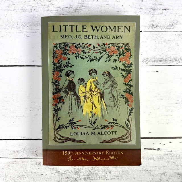 Little Women book with vintage cover art of 4 sisters surrounded by rose vines, laid on a rustic white wood floor