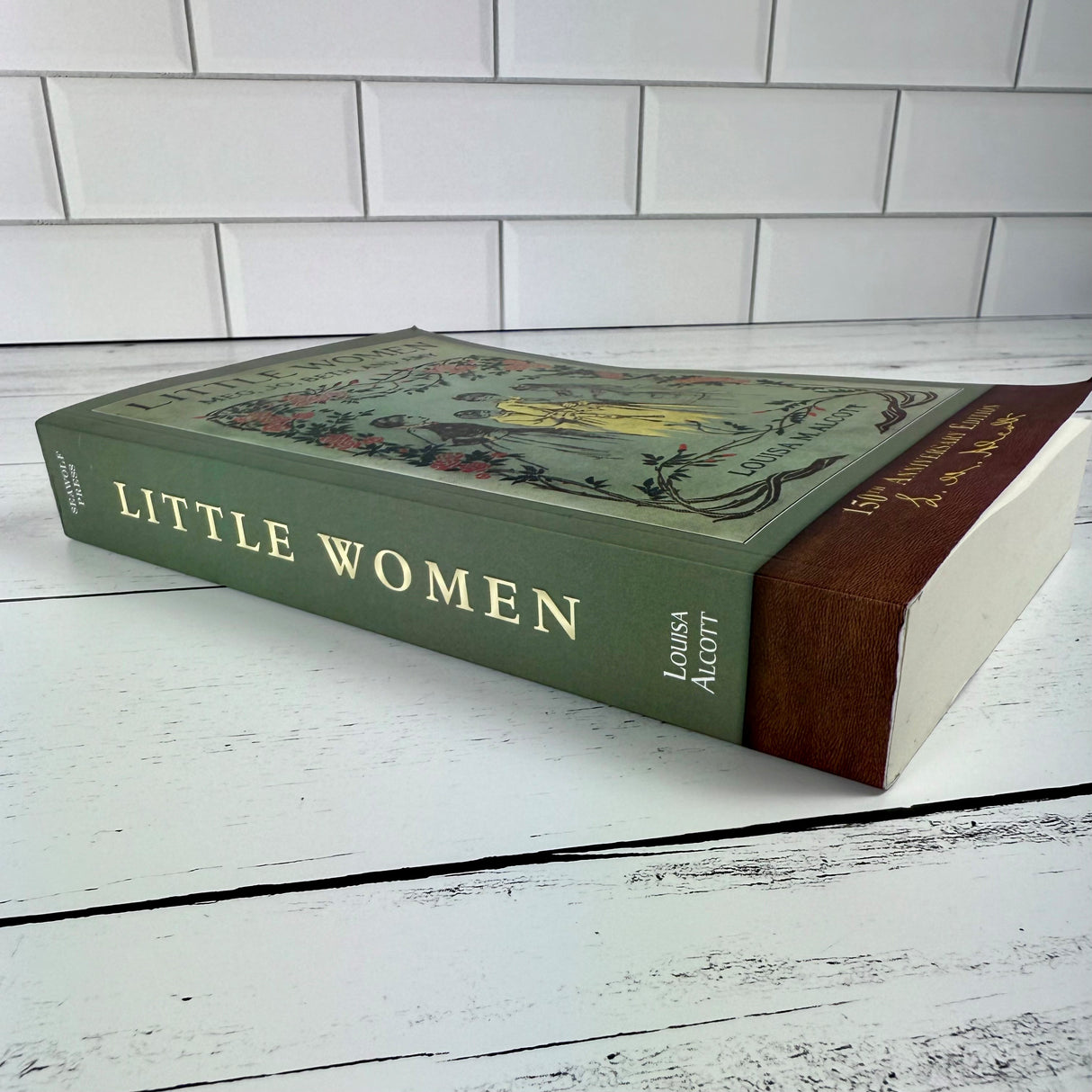 Little Women book laid on its side showing the generous width of the spine of the book