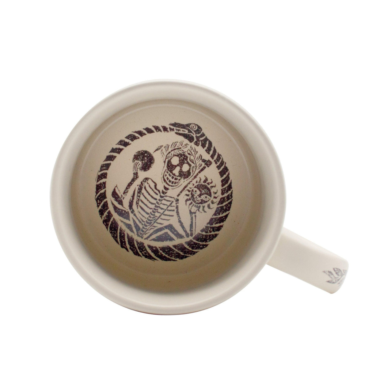 top down view of a White mug with a black skeleton design with ouroboros in the bottom of the mug on a white background