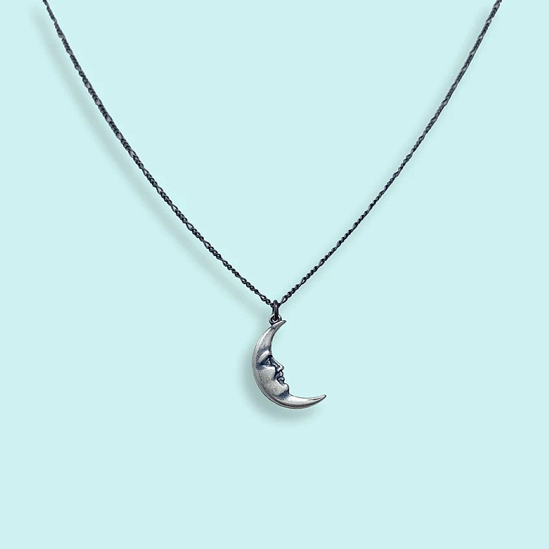 Crescent moon necklace on a light blue background