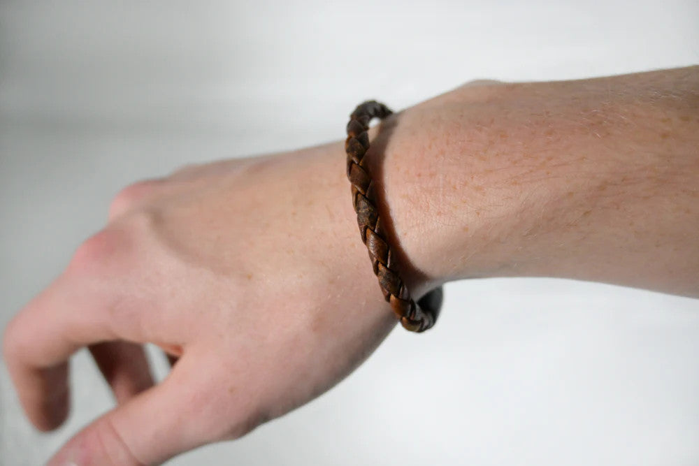 braided moose leather bracelet in a rich, deep brown leather worn on a model's hand showing the slim, yet masculine scale of the bracelet