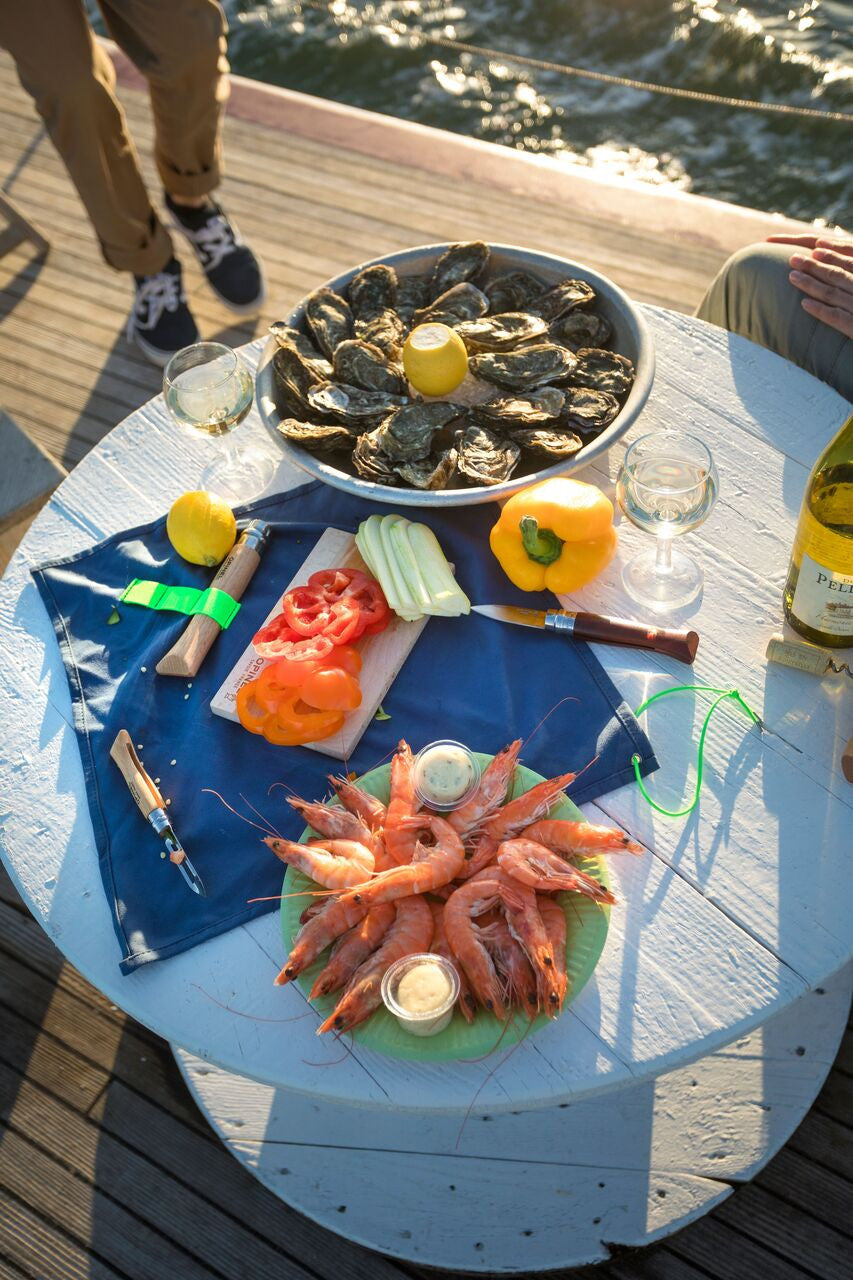 the nomad cooking kit amongst a spread of oysters and shrimp on a dockside table
